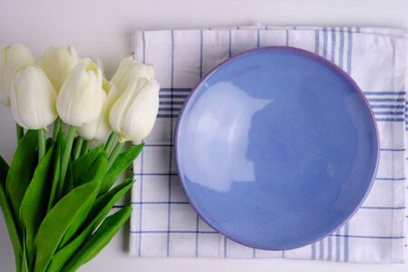 Top view of blank purple dish with a napkin on white wood background, with blank space and tulips decorated.の写真素材