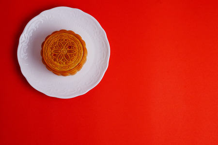Top view of Moon cake  on white plate and red background. Chinese mid autumn festival food, blank space.の写真素材
