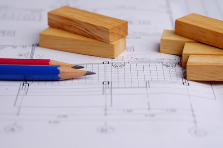 Close up of model wooden block and pencil on plan blueprints concept. Business concept of architect, designer and builder with draws a plan and design, selective focus.の写真素材