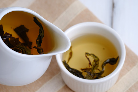 Pouring tea from a teapot into a cup on wooden table of nature, selective focus.の写真素材