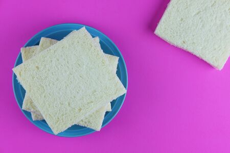 Top view of slice bread on blue plate and pink background concept, selective focus and copy space.
