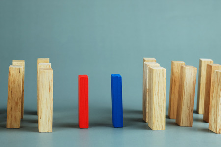 Blue and red wooden block standing from other standing in row on gray background. Business concept...