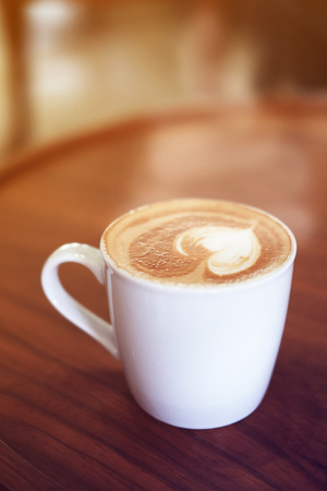Close up of hot coffee in cup on wood table design. Beautiful decorated with vintage tone concept, sunshine from window and selective focus.の写真素材