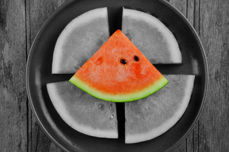 Top view of Watermelon slice on plate and wood table background. Black and white tone, vignette effect concept and selective focus with red watermelon.の写真素材