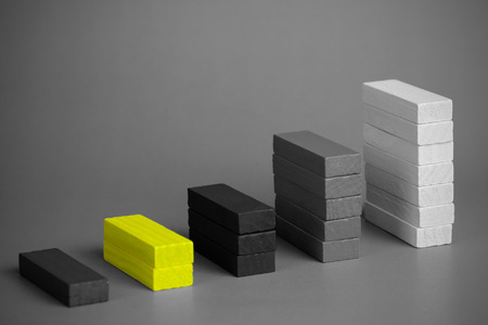 Close up of Color wood block with representing a graph, black and white tone, vignette effect and selective focus with yellow block. Business growth concept and copy space.の写真素材