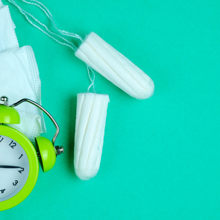 Woman hygiene protection of cotton tampons and sanitary pad on green background, woman menstruation cycle, critical day, selective focus and copy space.の写真素材