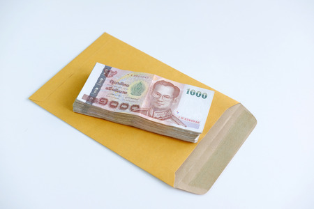 Close up of Thai money with one thousand baht banknotes on paper bag and white background, copy space and selective focus.の写真素材