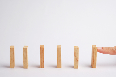 Wooden block standing with hand and outstanding among the collapse, business concept able to survive or dominant from destruction. Selective focus on gray background.の写真素材