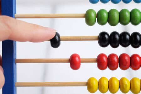 Close up of colorful abacus with counted by hand, traditional abacus in front of white background,...