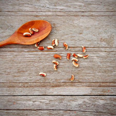 Grain of long beans on spoon and wooden background, copy space concept.
