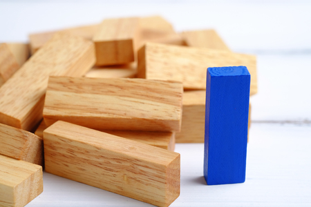 Blue one wooden block standing and outstanding among the collapse of fall in line, business concept able to survive or dominant from destruction. Selective focus on white wood background.の写真素材