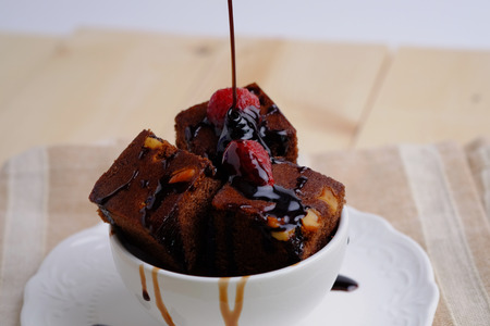 Close up of Chocolate brownies cake isolated with chocolate sauce and strawberry in white cup on wood table concept, decorated.の写真素材