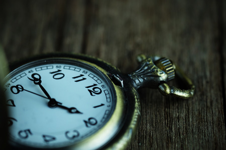 Close up of Vintage pocket watch on wood background, selective focus and vignette effect concept.の写真素材