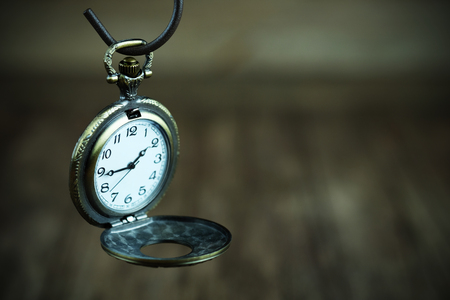 Close up of Vintage pocket watch on wood background, selective focus and vignette effect concept.の写真素材