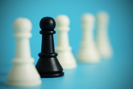 Close up of pawn chess with black in white group on  blue background. Business concept able to survive or dominant from competition, leadership, selective focus and vignette effect.の写真素材