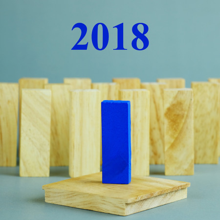 Blue one wooden block standing from other standing in row on gray background. Business concept with 2018 metaphor to leadership for survive. Selective focus dominant wooden block.の写真素材