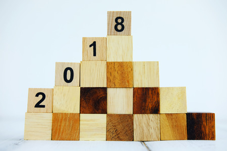 Happy new year 2018 on white wood block step stair of pyramid on wood background concept, close up and selective focus.の写真素材