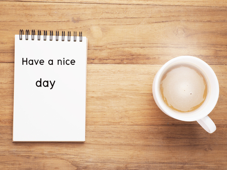 Have a nice day on note paper and coffee cup on wood table background, top view.の写真素材