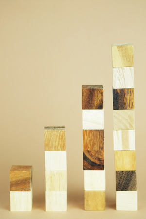 Square wood block of higher wooden block tower in form of graph shape, metaphor to business keep growing and rising or to complete.の写真素材