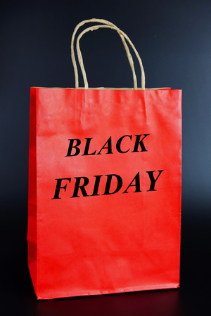 Red paper bag with Black friday concept on black background. Copy space and shopping lifestyle.の写真素材
