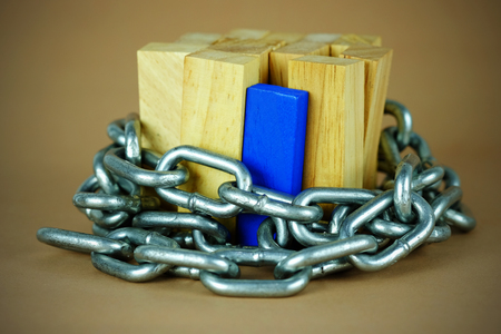 Wooden block standing and outstanding among the business trap with chain, business concept able to survive or dominant from destruction, selective focus and vignette effect.の写真素材