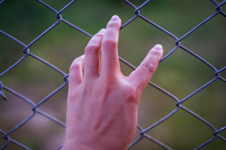 Hand in jail with girl and house of detention concept, vignette effect and selective focus.