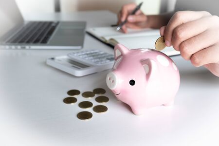 Modern woman putting Coin In pink Piggy Bank.の写真素材