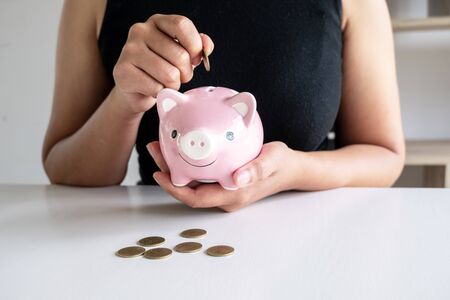 Woman in black shirt teach kits to putting Coin In pink Piggy Bank.の写真素材