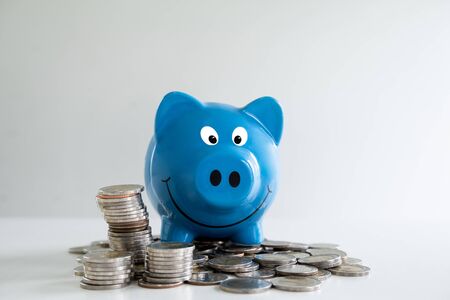 blue piggy bank saving money with coins pile.の写真素材
