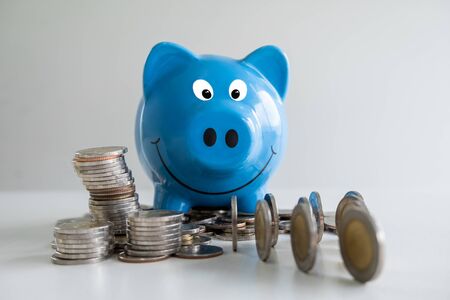 blue piggy bank saving money with coins pile.の写真素材