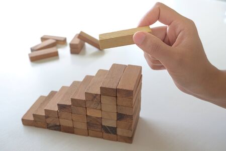 Image of hand holding blocks wood game to growing up of business. Risk of management and strategy plan.の写真素材