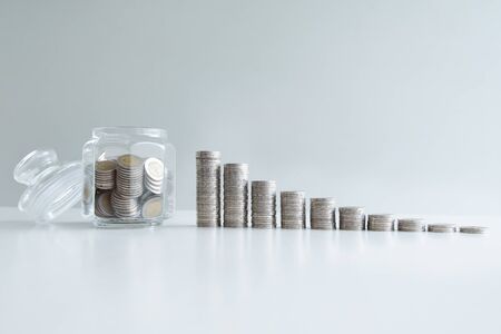 coin in glass bottle with coins bar graph, step up growing business to success and saving for retirement concept.の写真素材