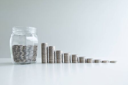 coin in glass bottle bank with coins bar graph, step up growing business to success and saving for retirement concept.の写真素材