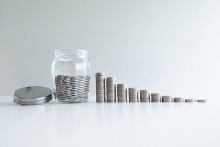 coin in glass bottle bank with coins bar graph, step up growing business to success and saving for retirement concept.の写真素材
