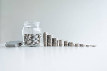 coin in glass bottle bank with coins bar graph, step up growing business to success and saving for retirement concept.の写真素材