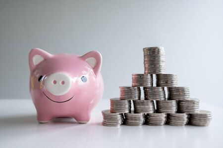 coin and pink piggy bank with coins pyramid, step up growing business to success and saving for retirement concept.の写真素材