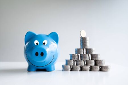 coin and blue piggy  bank with coins pyramid, step up growing business to success and saving for retirement concept.の写真素材