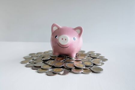 pink piggy bank with coins pile, step up growing business to success and saving for retirement concept.の写真素材