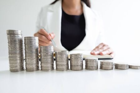 woman hand writing coins from her coins bar graph, step up growing business to success and saving for retirement concept.の写真素材