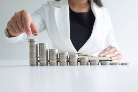 one woman putting coin on growth coins bar graph in white suit, step up growing business to success and saving for retirement concept.の写真素材