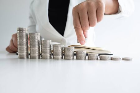 one woman putting coins on growth coins bar graph in white suit, step up growing business to success and saving for retirement concept.の写真素材