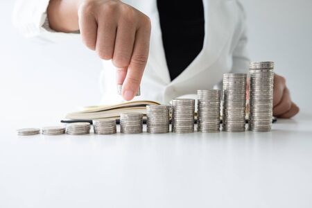 one woman putting coins on growth coins graph in white suitstep up growing business to success and saving for retirement concept.の写真素材