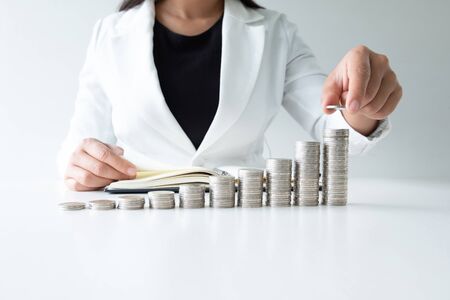 one woman putting coin on growth coins graph in white suit, step up growing business to success and saving for retirement concept.の写真素材