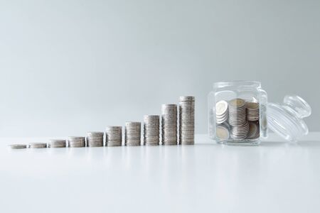 coin saving in glass bottle with coins bar graph, step up growing business to success and saving for retirement conceptの写真素材