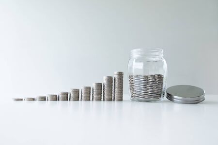 coin in glass bottle bank with coins bar graph, step up growing business to success and saving for retirement conceptの写真素材
