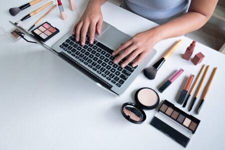 woman blogger present cosmetic product sitting in front tablet and broadcast to social network by...