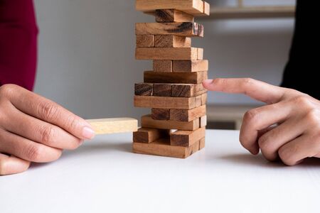 Two hands playing blocks wood game, gambling placing wooden block. Concept Risk of management and strategy plan, growth business success process and team work.の写真素材