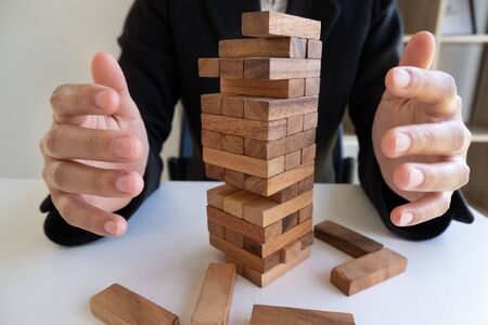 Hands prevent blocks wood, gambling placing wooden block. Concept Risk of management and strategy plan.の写真素材