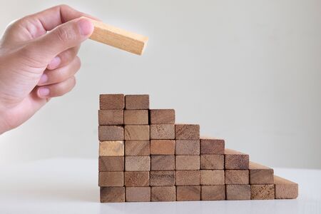 Image of hand holding blocks wood game to growing up of business. Risk of management and strategy plan.の写真素材