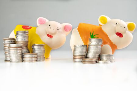 Yellow and Orange piggy bank saving money with coins pile.の写真素材